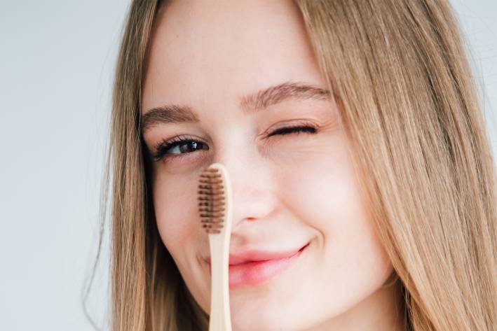 a girl holding a bamboo toothbrush