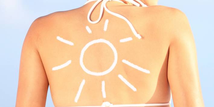 Sunscreen shaped like sun on woman's back
