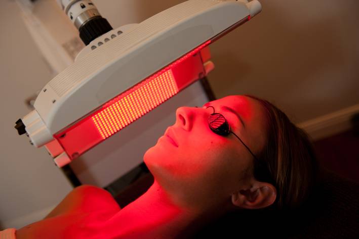 a woman having red light therapy applied to her face