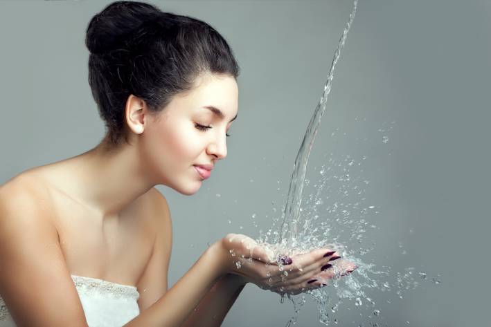 Woman with water pouring into her hands.