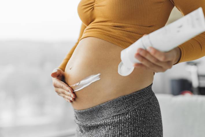 a pregnant woman applying cream to help with stretch marks