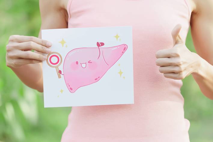 a woman holding a cartoon illustration of a happy, healthy liver