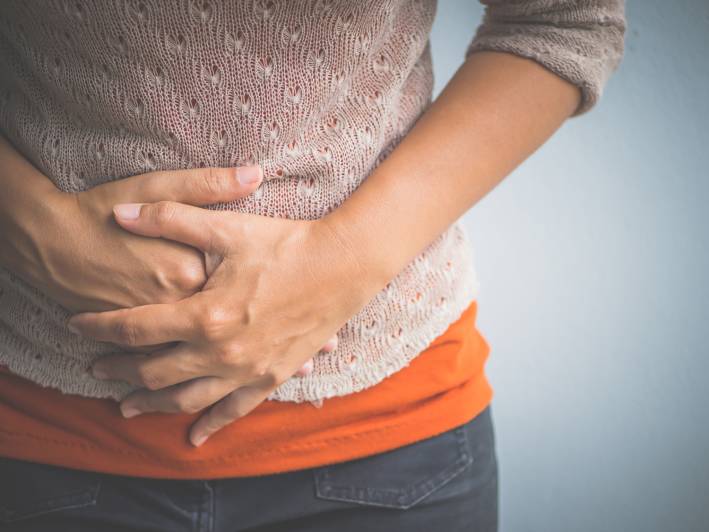 A woman holding stomach with bloating discomfort.