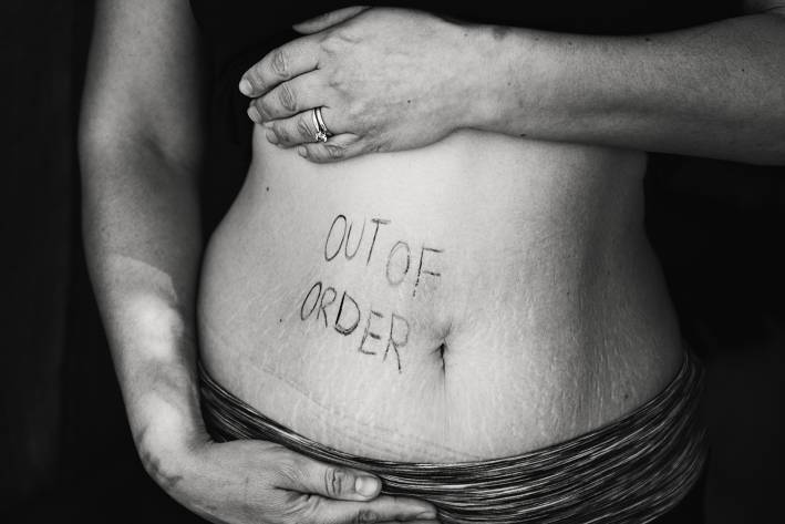 A woman with an "out of order" sign written on her belly