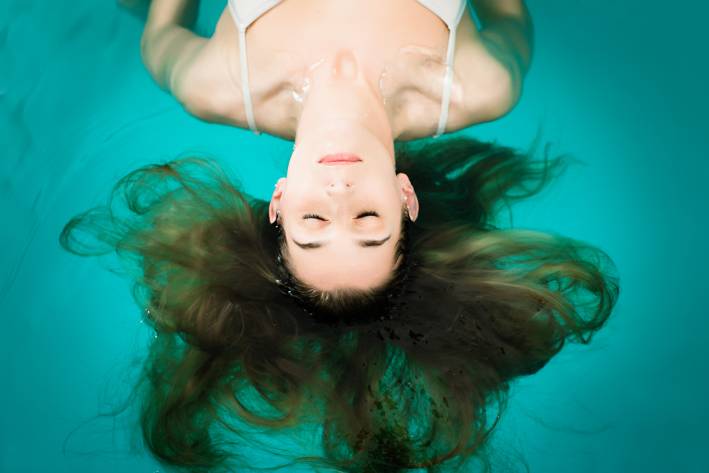 A woman floating in the water of a flotation tank in a relaxed state.