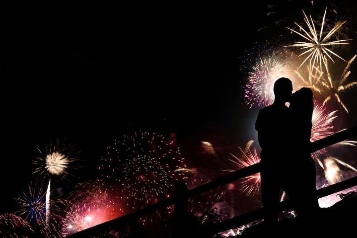 lovers kissing in front of a sky full of fireworks