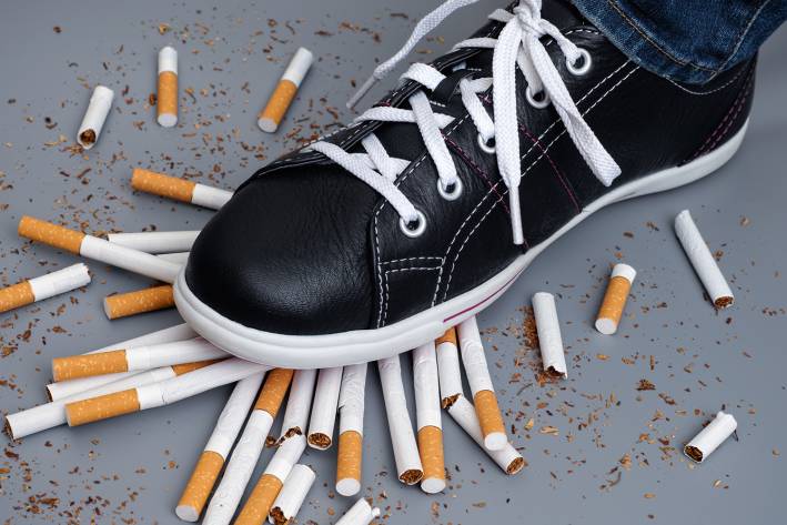 a man stomping on a pile of broken cigarettes