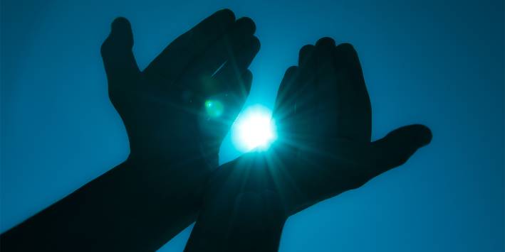 Hands cupped around a ball of healing light