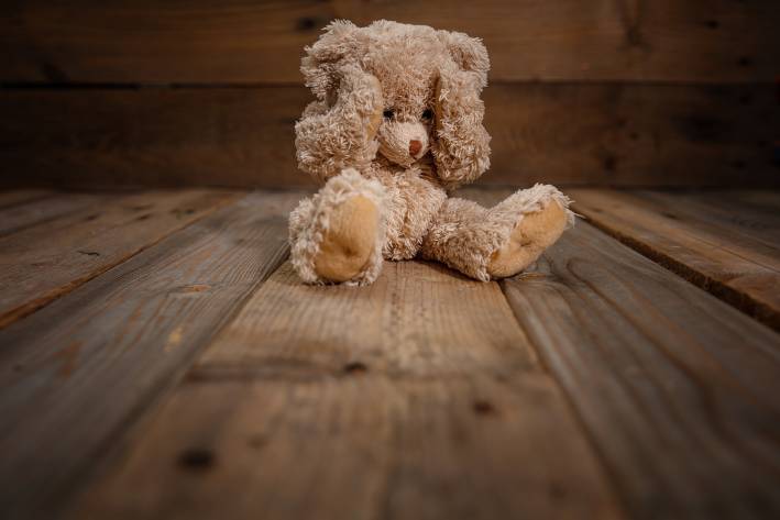 a traumatized teddy bear sitting on the floor