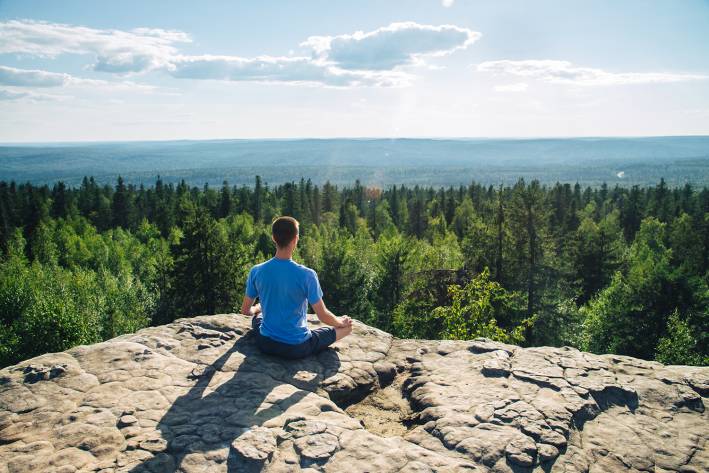 a man meditating on a mountain top with a beautiful view