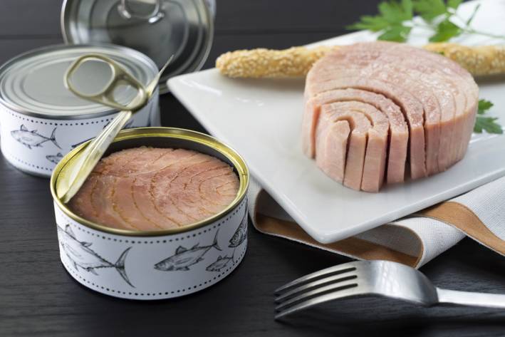 cans of tuna and some fish on a cutting board