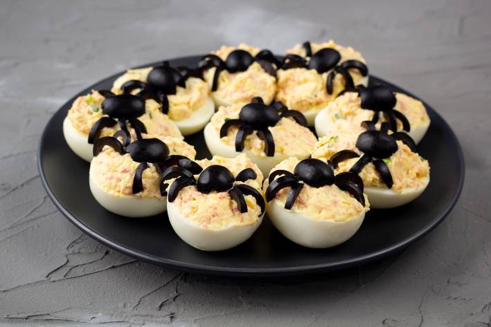 deviled eggs with black olive spiders