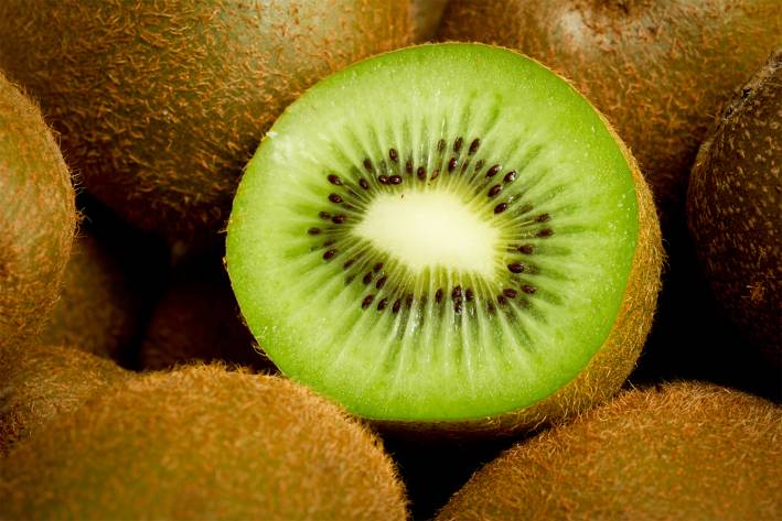 a sliced kiwi surrounded by whole kiwifruit