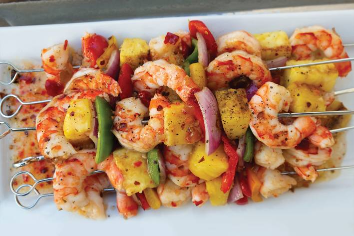 Cooked shrimp kebobs on a serving white plate.