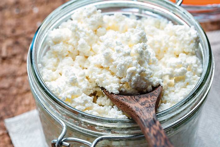 Homemade ricotta cheese is a jar with a wooden spoon.