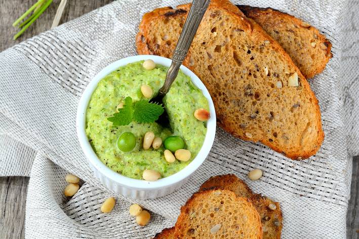 a bowl of pea dip and some toasted bread