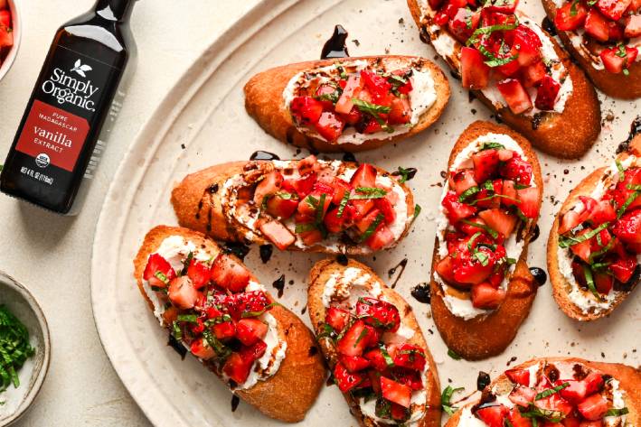 a plate of bruschetta with strawberries, goat cheese, and balsamic