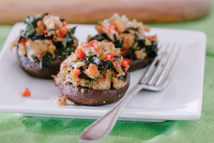 Stuffed crimini mushrooms on a white square plate with fork.