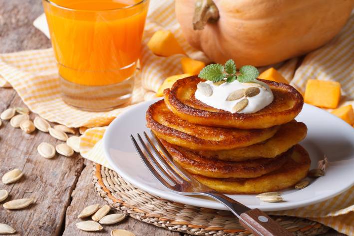 a stack of pumpkin pancakes and a glass of orange juice