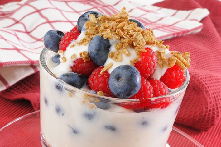 a yogurt parfait with granola, nuts, and berries in a glass
