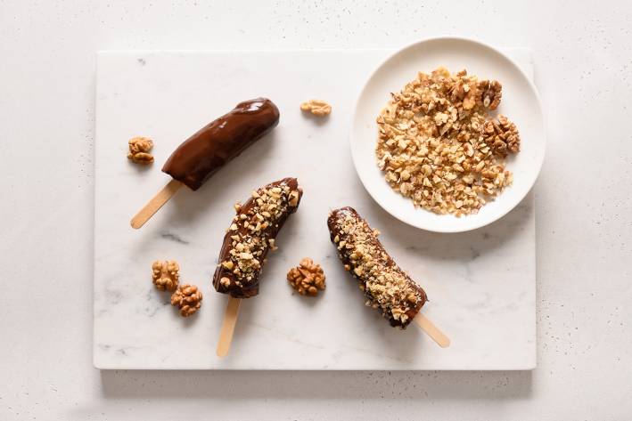 frozen banana pops rolled in chocolate with nuts on top