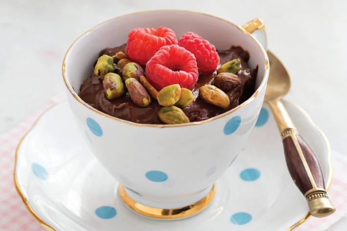 A dish of chocolate pudding with raspberries and pistachios