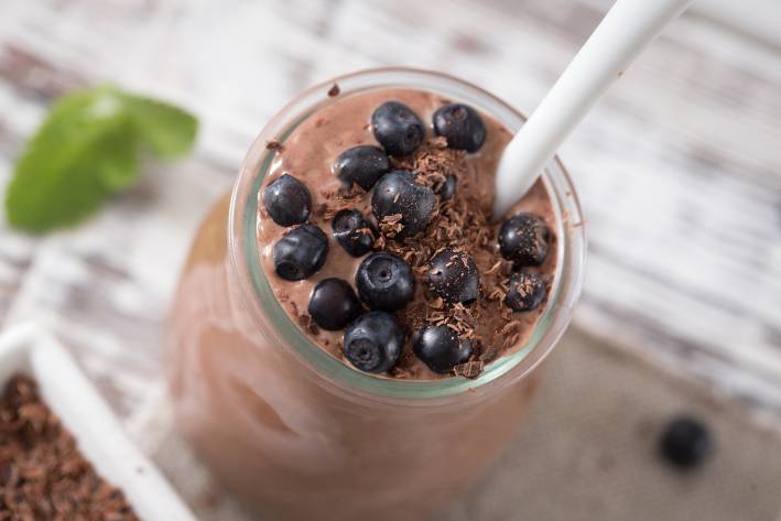 a dish of creamy chocolate mousse topped with berries and seeds