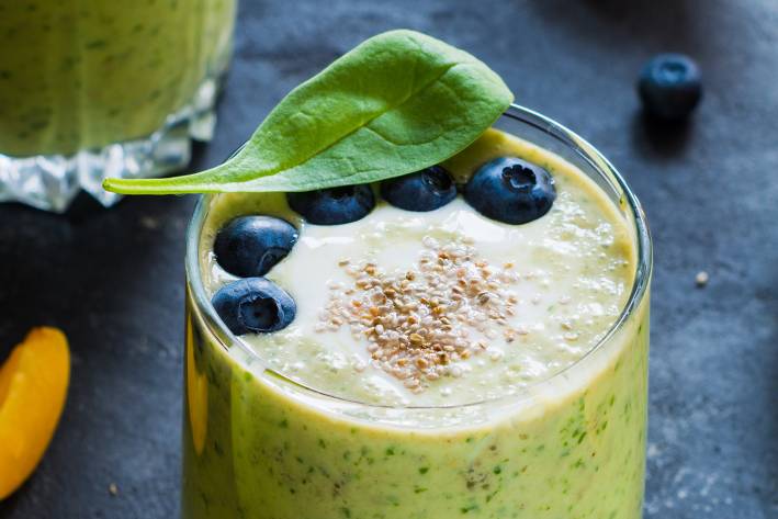 a smoothie made with bananas, blueberries, seeds, and spinach