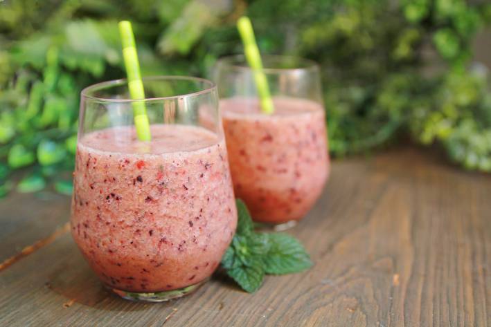 two berry smoothies in glass cups with straws