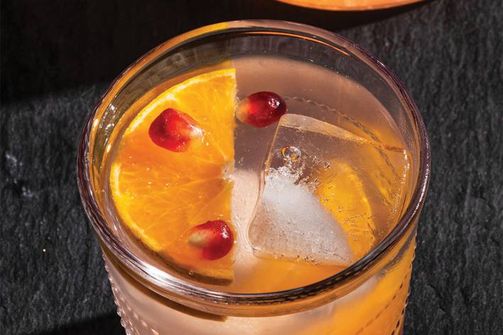 a glass of citrus and pomegranate mocktail