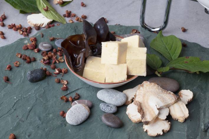Shiitake mushrooms, tofu and basil ingredients for recipe on a stone slab.