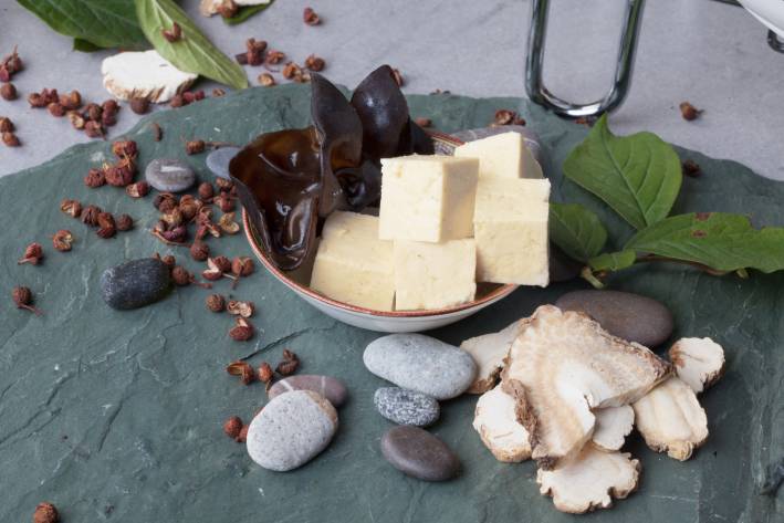 Shiitake mushrooms, tofu and basil on a stone slab.