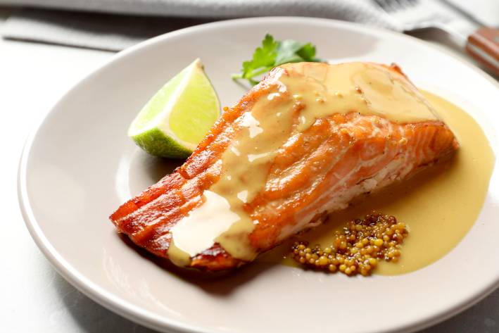 a salmon filet on a plate with mustard