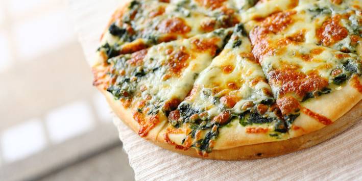 Spinach pizza with cheese on white table