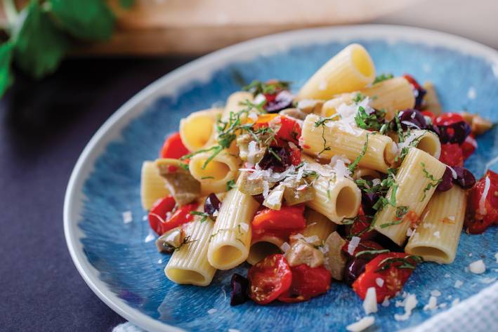 Rigatoni with Fresh Cherry Tomatoes and Olives on a blue plate ready to serve.