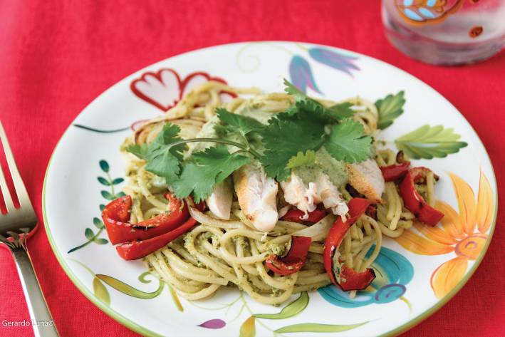 Roasted Poblano Creamy Spaghetti with Grilled Chicken, Onions, & Peppers on a colorful plate with a red tablecloth background.
