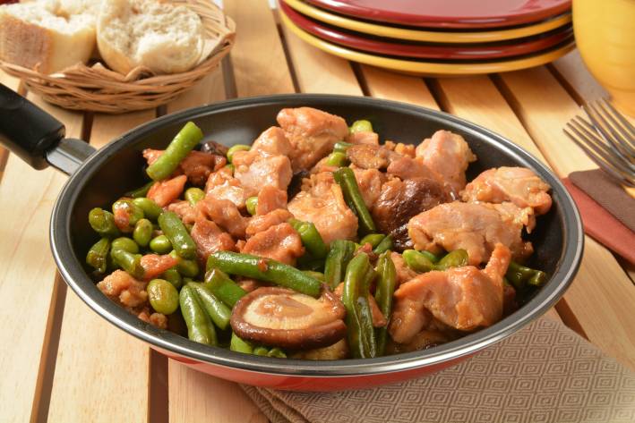 a skillet full of chicken, green beans, and shiitake mushrooms