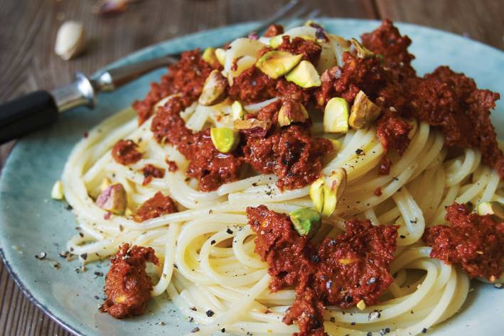 Spaghetti with Sun-Dried Tomato and Pistachio Pesto on a blue plate.