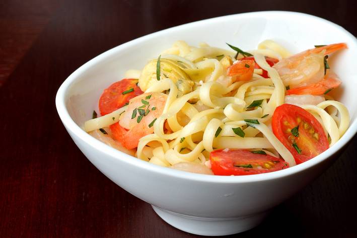 Summer Shrimp Linguine with Tomatoes & Artichokes served in a white bowl.