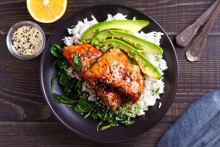 pan-seared salmon with sesame seeds on a bed of rice and greens