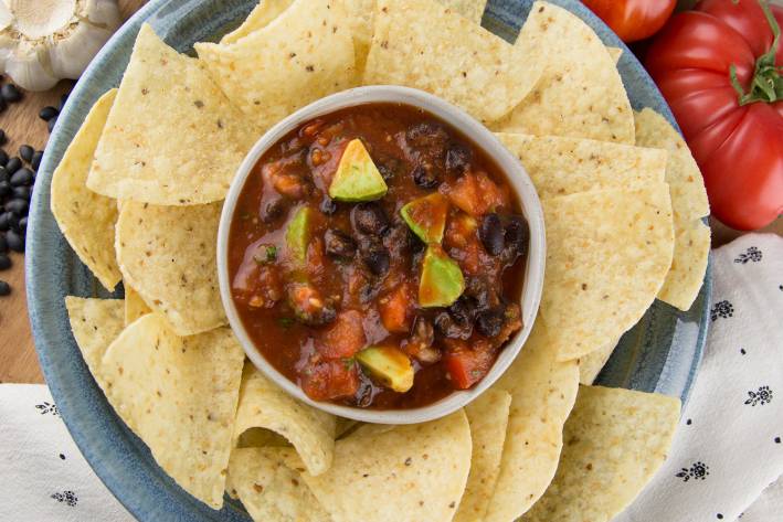 a bowl of chunky salsa surrounded by tortilla chips