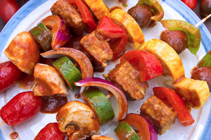 A plate of skewered vegetables and tempeh