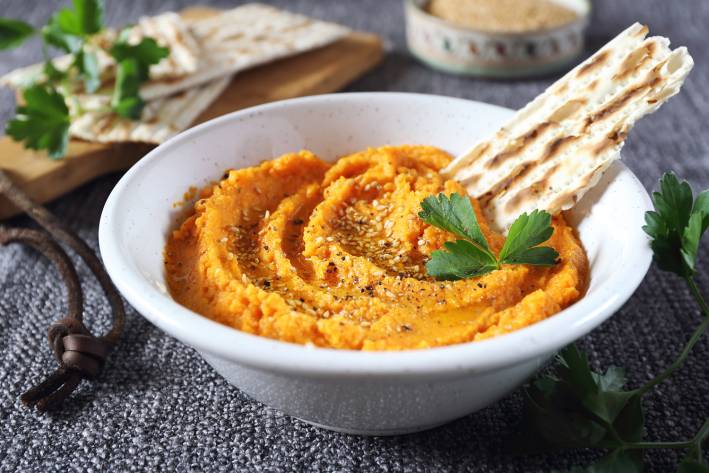 a bowl of carrot dip ready for a party