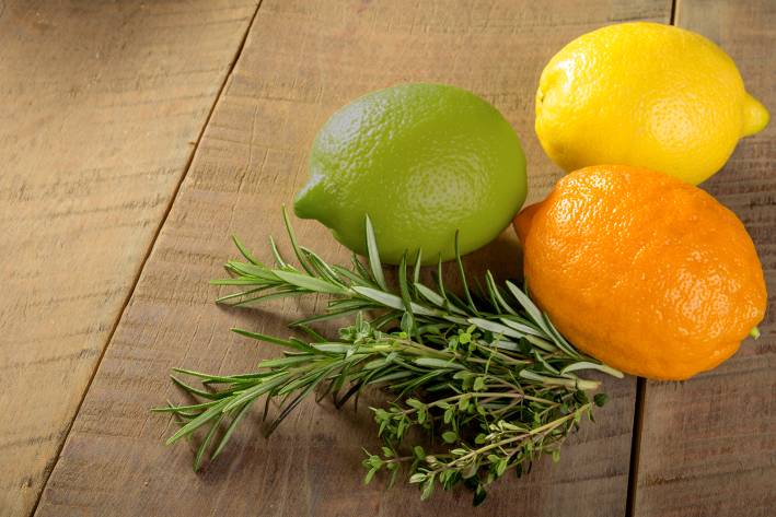 a lemon, a lime, an orange, and a sprig of rosemary