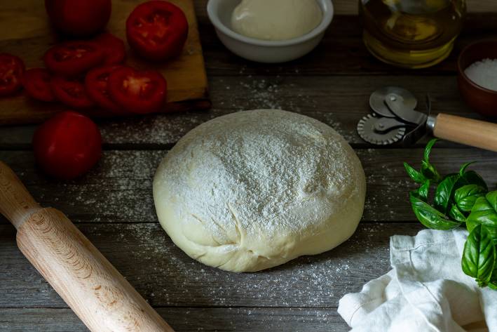 a ball of floured pizza dough and other ingredients