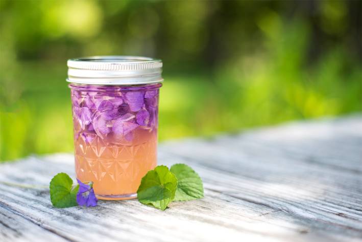 a jar of violet petals soaking into vinegar