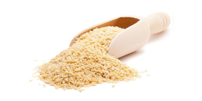 Short grain rice spilling from wooden scoop.