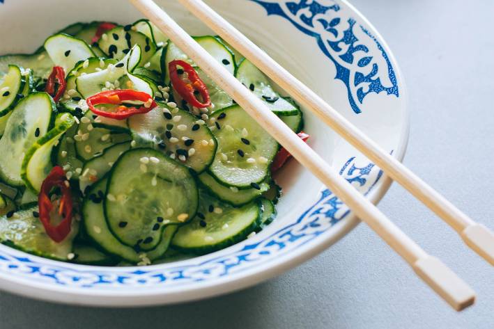 Chopsticks resting on a bowl of Thai cucumber salad