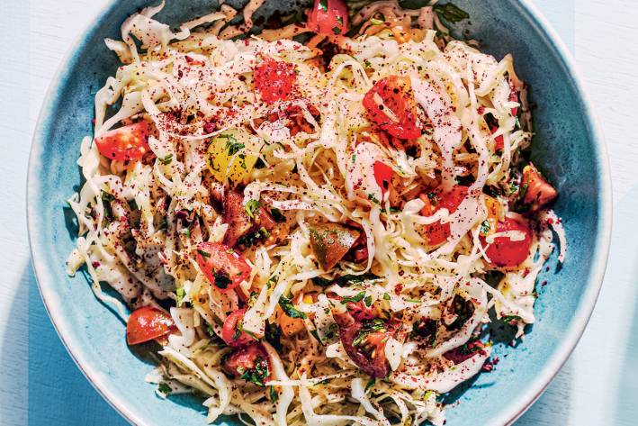 a bowl of cabbage, cherry tomatoes, parsley, and spices