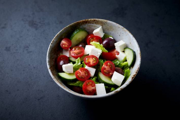 a bowl of greek salad with cucumbers, olives, and cherry tomatoes